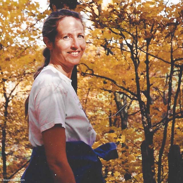 woman surrounded by trees in the fall